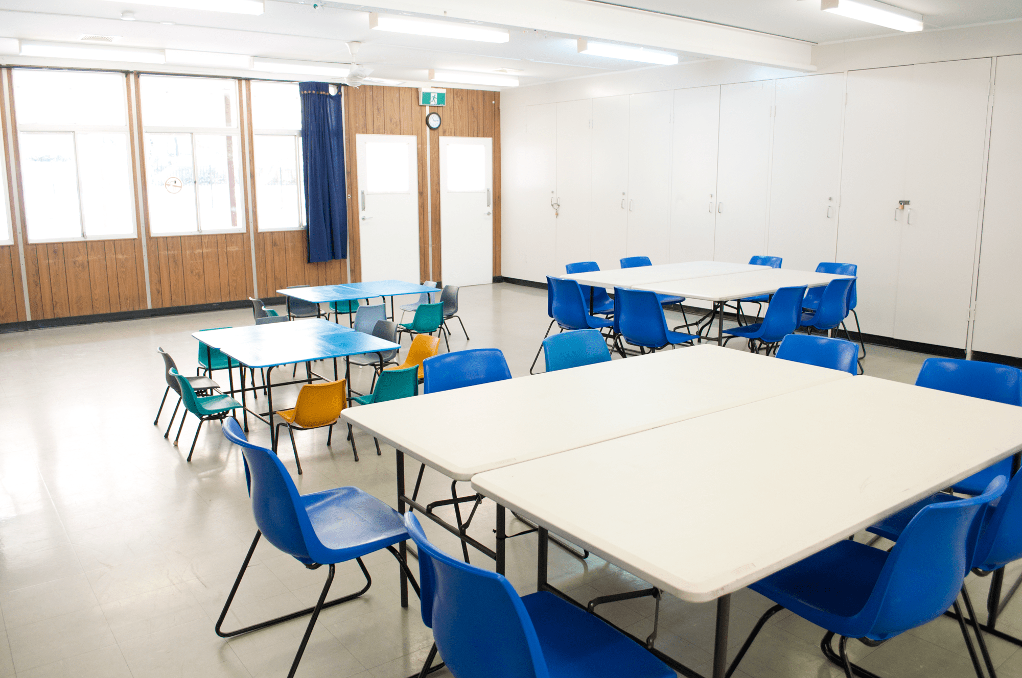 Interior of Nellie Hall showing tables and chairs set up for a meal, craftgroup or playgroup.